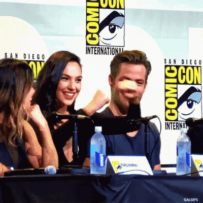 A Group Of People Sitting At A Table With A Comic Con Logo Behind Them GIF