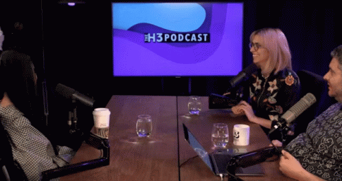A Group Of People Sitting At A Table With Microphones And A Screen That Says H3podcast GIF