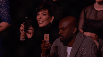 A Group Of People Sitting In A Dark Room With One Man Wearing A Sweater That Says Cbs On It GIF