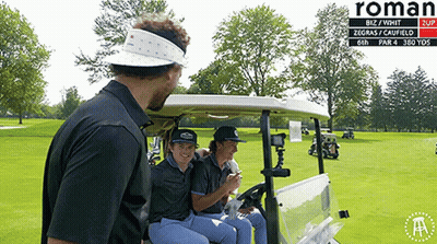 A Group Of People Sitting In A Golf Cart On A Golf Course With Roman Written On The Bottom GIF