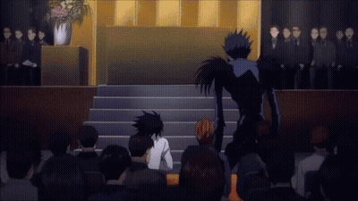 A Group Of People Sitting In Front Of A Podium With A Man In A Black Suit Standing Behind Them GIF