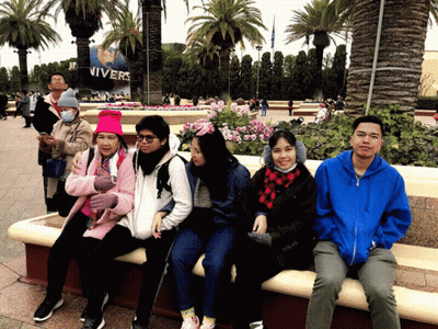 A Group Of People Sitting On A Bench In Front Of A Sign That Says Nivers GIF