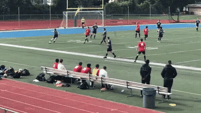 A Group Of People Sitting On A Bench Watching A Soccer Game With A Player Wearing A Red Jersey With The Number 19 On It GIF
