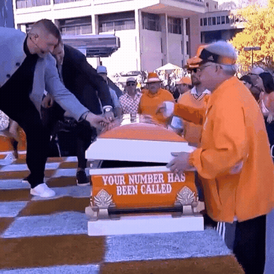 A Group Of People Standing Around A Coffin That Says " Your Number Has Been Called " GIF