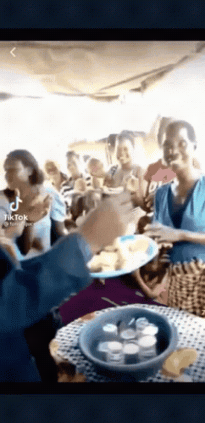 A Group Of People Standing Around A Table Eating Food . GIF