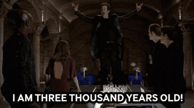 A Group Of People Standing Around A Table With The Words " I Am Three Thousand Years Old " On It GIF
