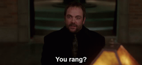 A Group Of People Standing Around A Table With The Words " You Rang " In White Letters GIF