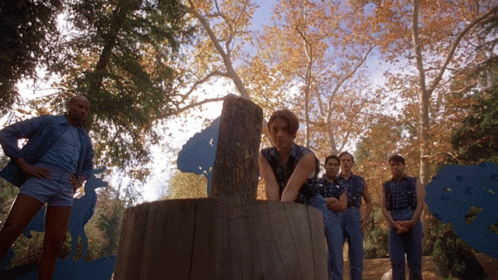 A Group Of People Standing Around A Tree Trunk GIF