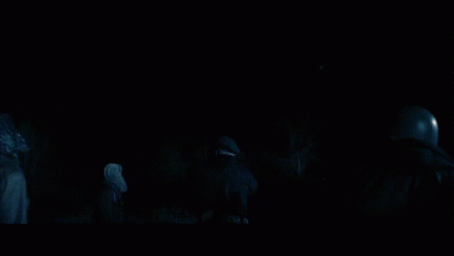 A Group Of People Standing In A Dark Room Looking At Something GIF
