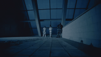 A Group Of People Standing In A Dark Room With A Blue Sky In The Background GIF