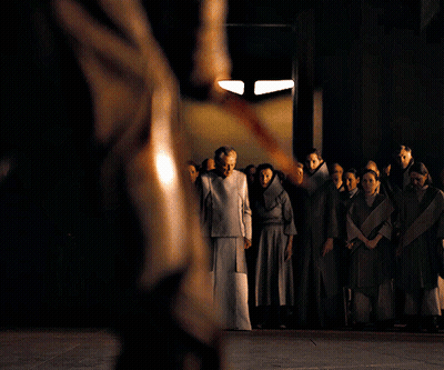 A Group Of People Standing In A Dark Room With A Man Holding A Sword GIF