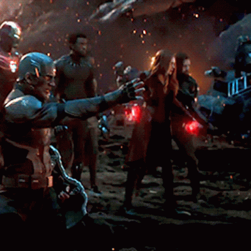 A Group Of People Standing In A Dark Room With A Man Pointing At Something GIF