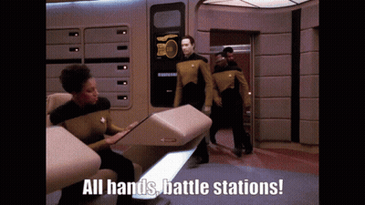 A Group Of People Standing In A Room With The Words " All Hands Battle Stations " On The Bottom GIF
