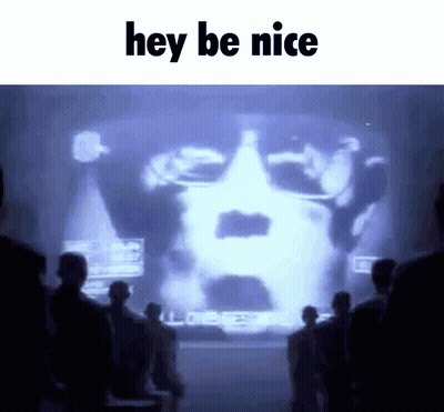 A Group Of People Standing In Front Of A Large Screen That Says Hey Be Nice GIF