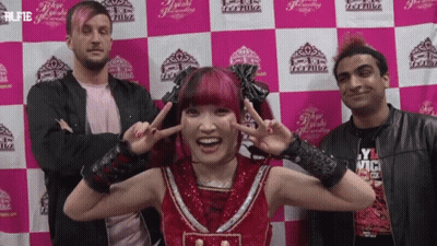 A Group Of People Standing In Front Of A Pink And White Checkered Wall With The Word Tokyo On It GIF