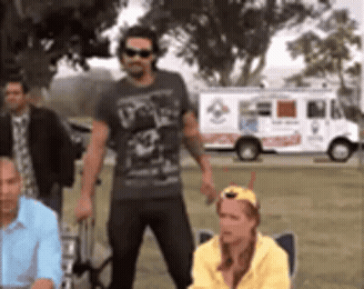A Group Of People Standing In Front Of A Pizza Truck . GIF