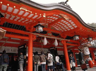 A Group Of People Standing In Front Of A Red Building With Lanterns Hanging From The Ceiling GIF