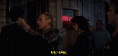 A Group Of People Standing In Front Of A Sign That Says Heineken GIF