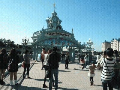 A Group Of People Standing In Front Of A Tokyo Disneyland Gate GIF