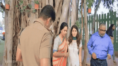 a group of people standing in front of a tree with a man in a police uniform