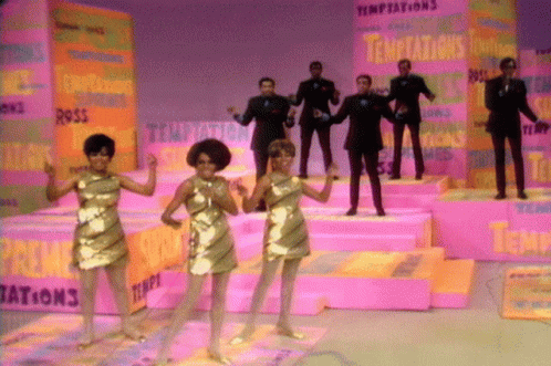 A Group Of People Standing In Front Of A Wall That Says Temptations On It GIF