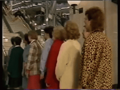 A Group Of People Standing Next To Each Other In Front Of A Staircase GIF