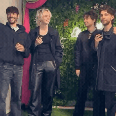 A Group Of People Standing Next To Each Other In Front Of A Wall . GIF