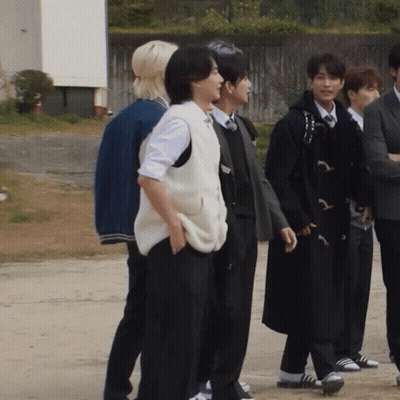 A Group Of People Standing Next To Each Other With One Wearing A Vest GIF