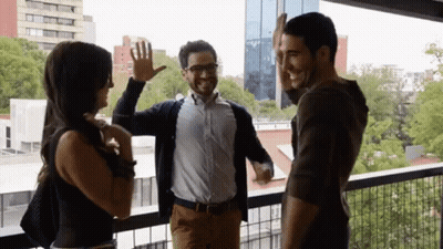 A Group Of People Standing On A Balcony Giving Each Other A High Five GIF