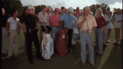 A Group Of People Standing On A Golf Course With A Man Holding A Golf Bag That Says Taylormade On It . GIF