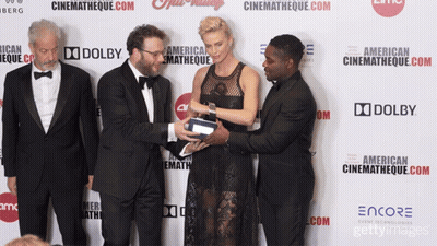 A Group Of People Standing On A Red Carpet With A Sign That Says Dolby GIF