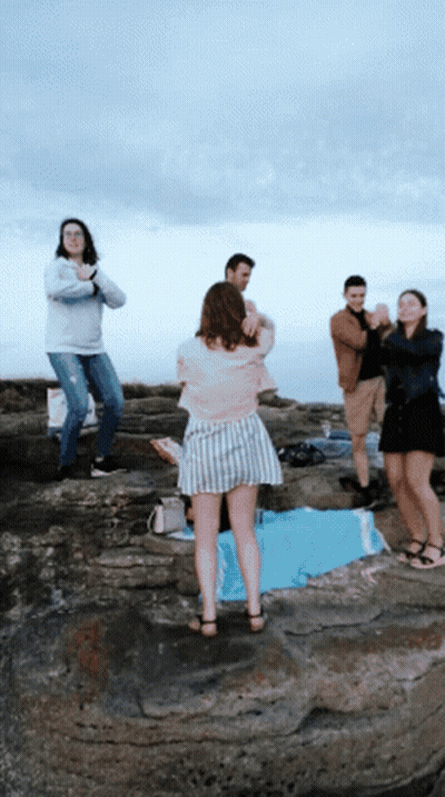 A Group Of People Standing On A Rocky Cliff With A Woman Taking A Picture GIF