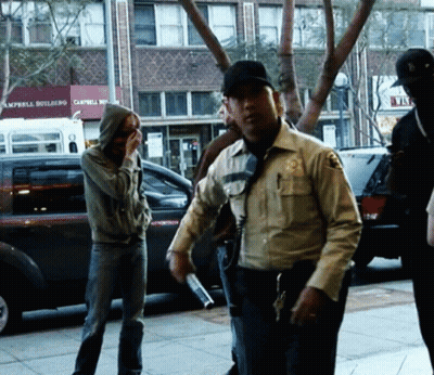 A Group Of People Standing On A Sidewalk In Front Of A Building That Says Campbell Building GIF