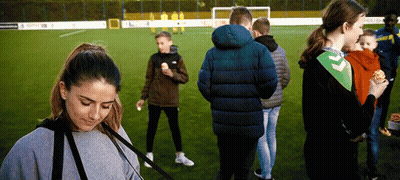 A Group Of People Standing On A Soccer Field Eating Hamburgers GIF