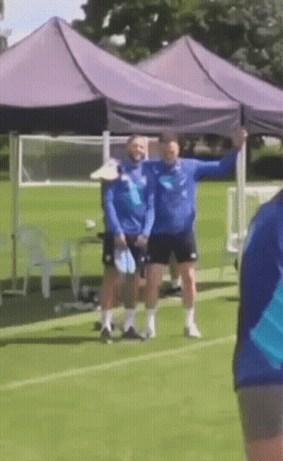 A Group Of People Standing On A Soccer Field Under A Purple Tent GIF