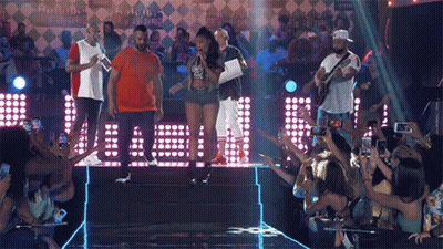 A Group Of People Standing On A Stage In Front Of A Crowd Taking Pictures GIF