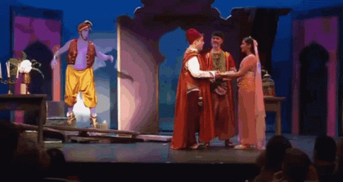 A Group Of People Standing On A Stage With A Man In A Turban Standing Behind Them GIF