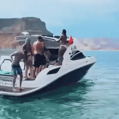 A Group Of People Standing On Top Of A Boat In The Water . GIF