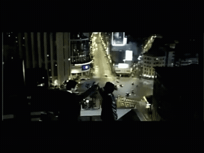 A Group Of People Standing On Top Of A Building Overlooking A City At Night GIF