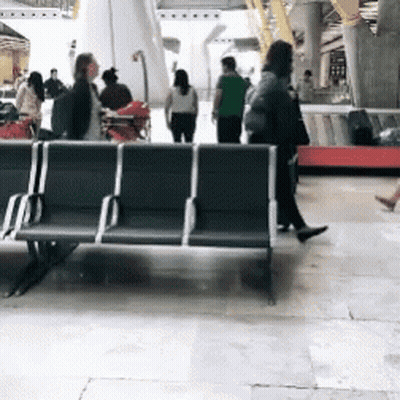 A Group Of People Walking Around A Waiting Area GIF