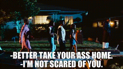 A Group Of People Walking In Front Of A House At Night With The Words Better Take Your Ass Home I 'M Not Scared Of You GIF
