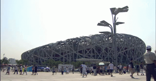 A Group Of People Walking In Front Of A Large Building GIF