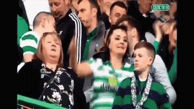 A Group Of People Watching A Soccer Game With A Sign That Says Celtic Tv GIF
