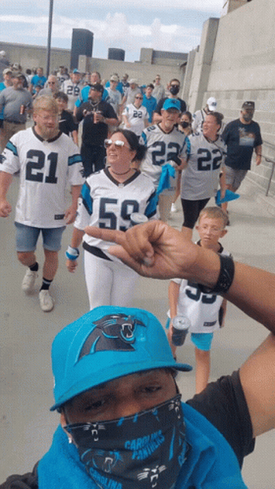 A Group Of People Wearing Carolina Panthers Jerseys Are Walking GIF