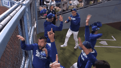 A Group Of People Wearing Dodgers Hoodies Are Dancing On A Baseball Field GIF