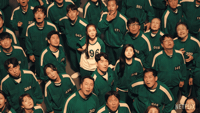A Group Of People Wearing Green Uniforms With Numbers On Them Are Looking Up GIF