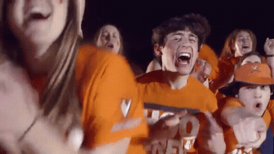 A Group Of People Wearing Orange Shirts And Hats Are Standing In A Crowd . GIF