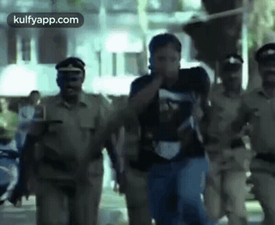 A Group Of Police Officers Are Carrying A Man Down A Street In A Blurry Photo . GIF