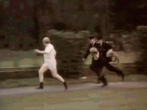 A Group Of Police Officers Are Chasing A Man Who Is Running Down The Street . GIF