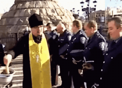 A Group Of Police Officers Are Gathered Around A Priest GIF